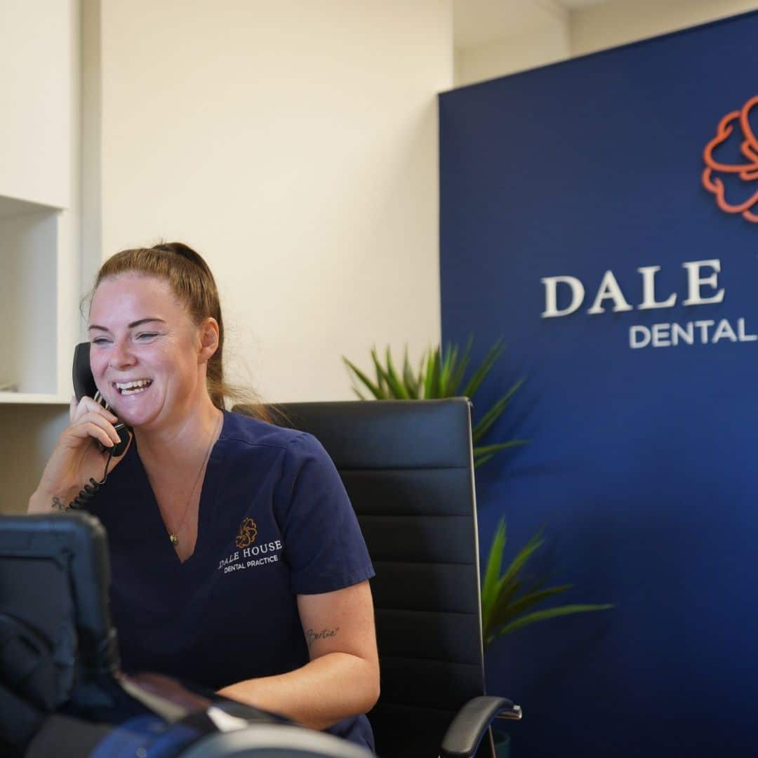 Smiling dental receptionist on phone at Dale House Dental