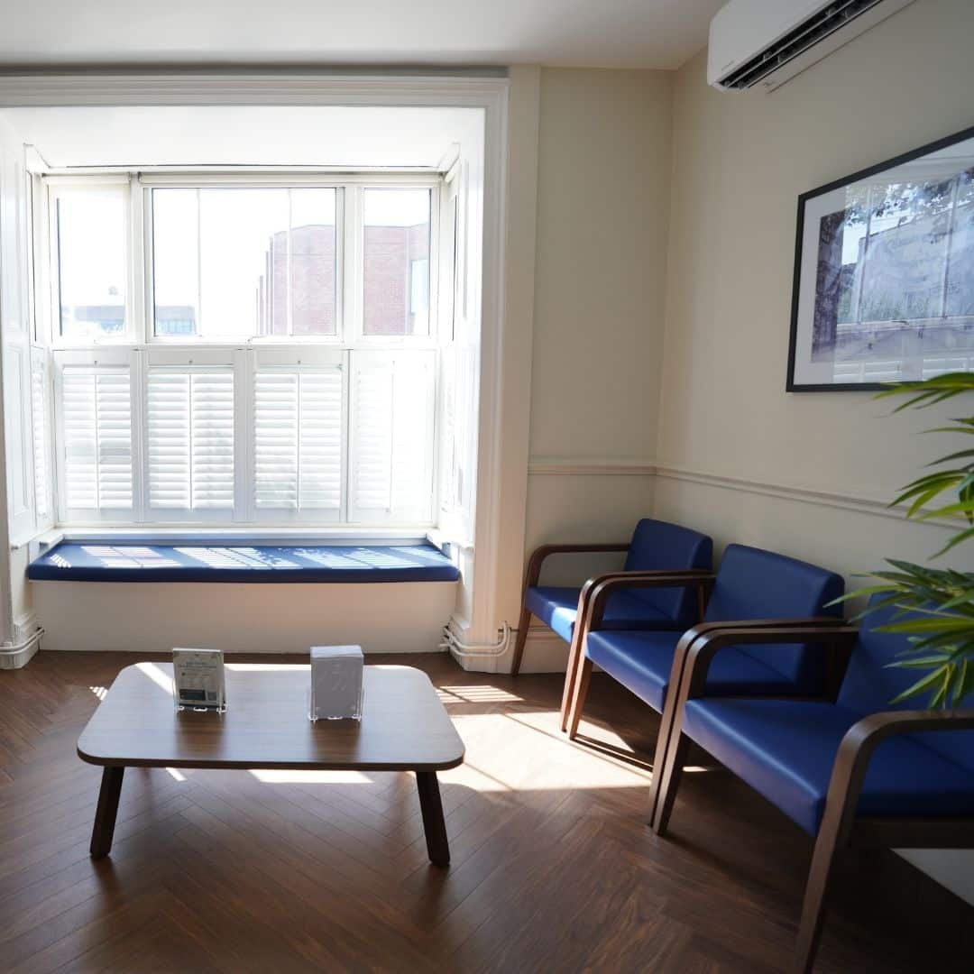 Bright medical waiting room with blue chairs and window